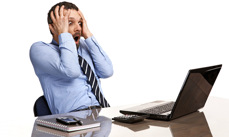 panicking businessman in horror looking at the laptop screen - isolated on white background