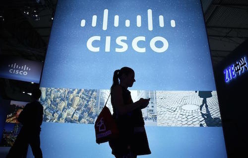 A visitor walks past a Cisco advertising panel as she looks at her mobile phone at the Mobile World Congress in Barcelona