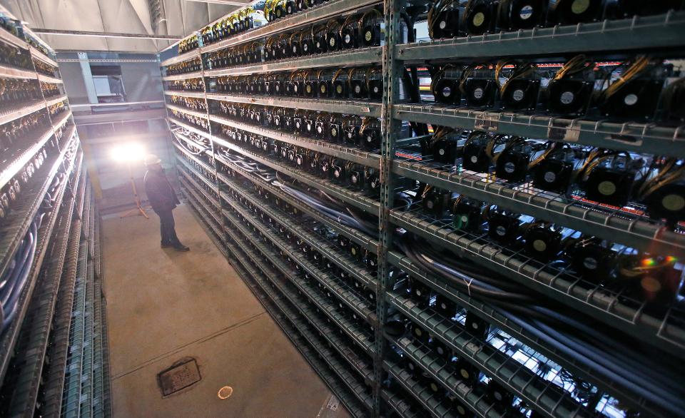 Workers look over racks of Bitcoin data miners during construction of a Bitcoin data center in... (+) Virginia Beach, Va., Friday, Feb. 9, 2018. (AP Photo/Steve Helber)