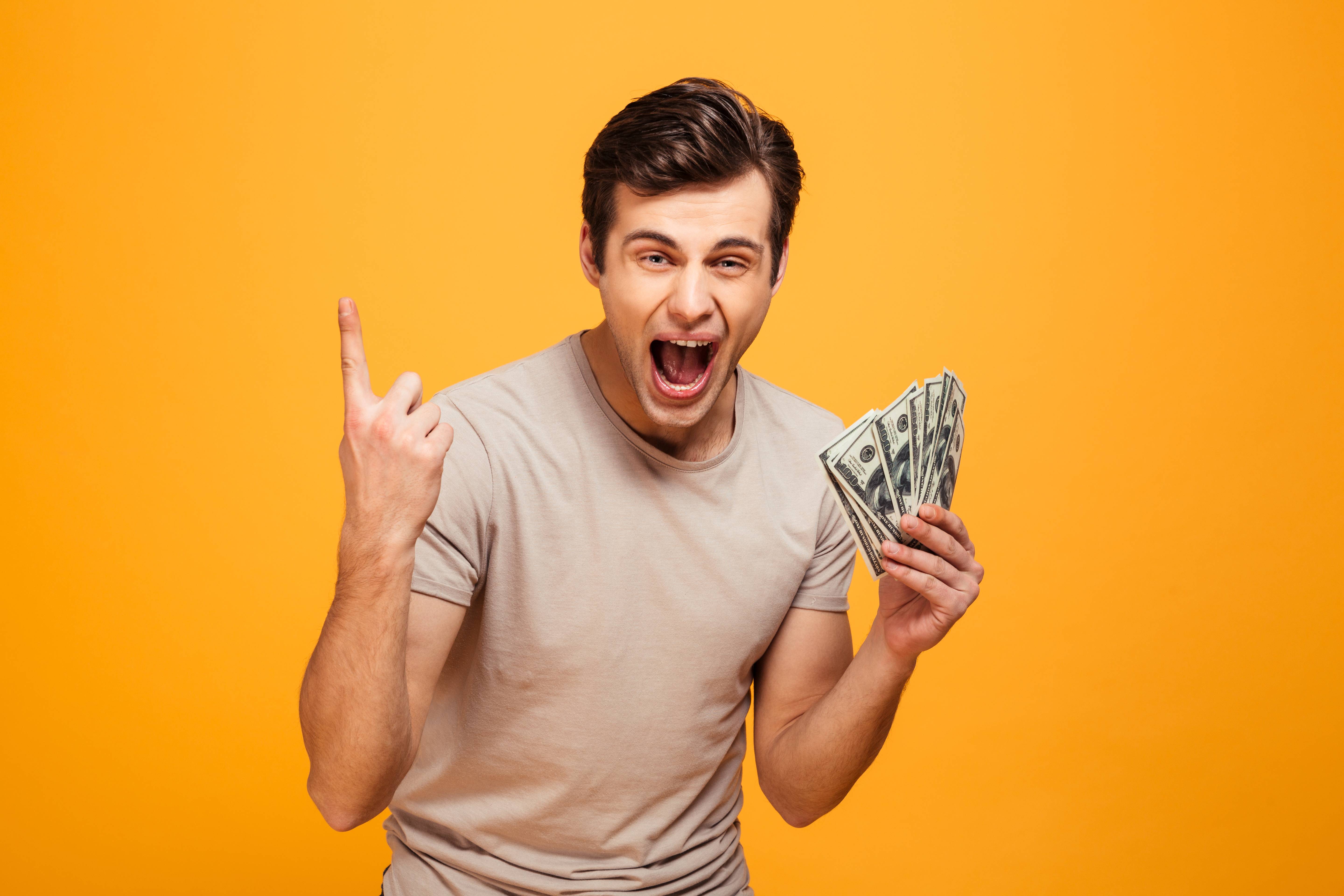 Portrait of an excited young man holding money